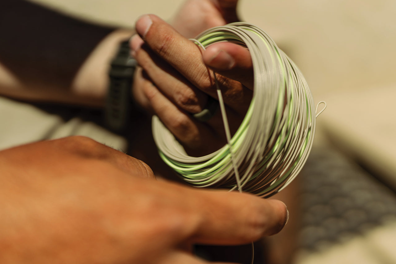 Close-up of hands holding a spool of green and white fly line