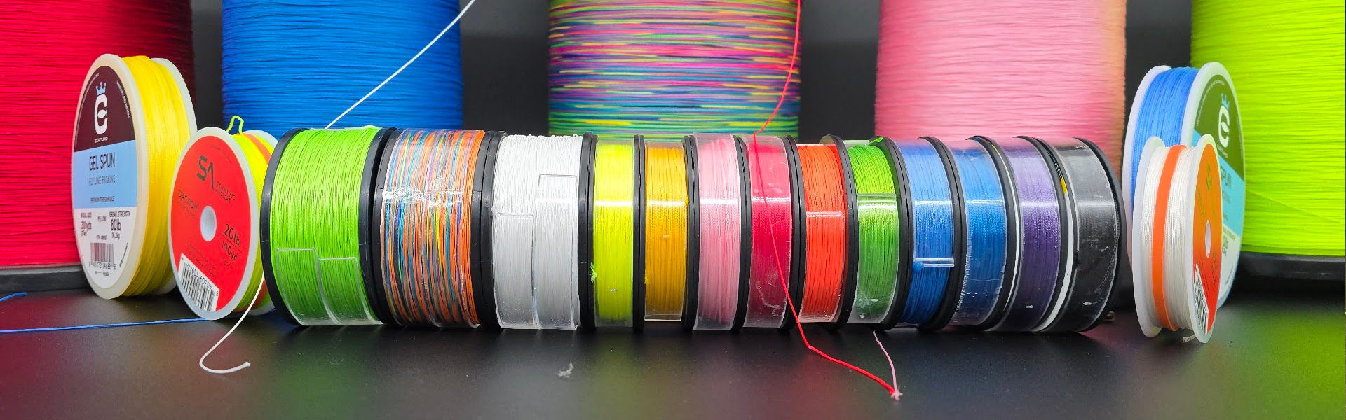 Assorted spools of colorful backing on a dark surface