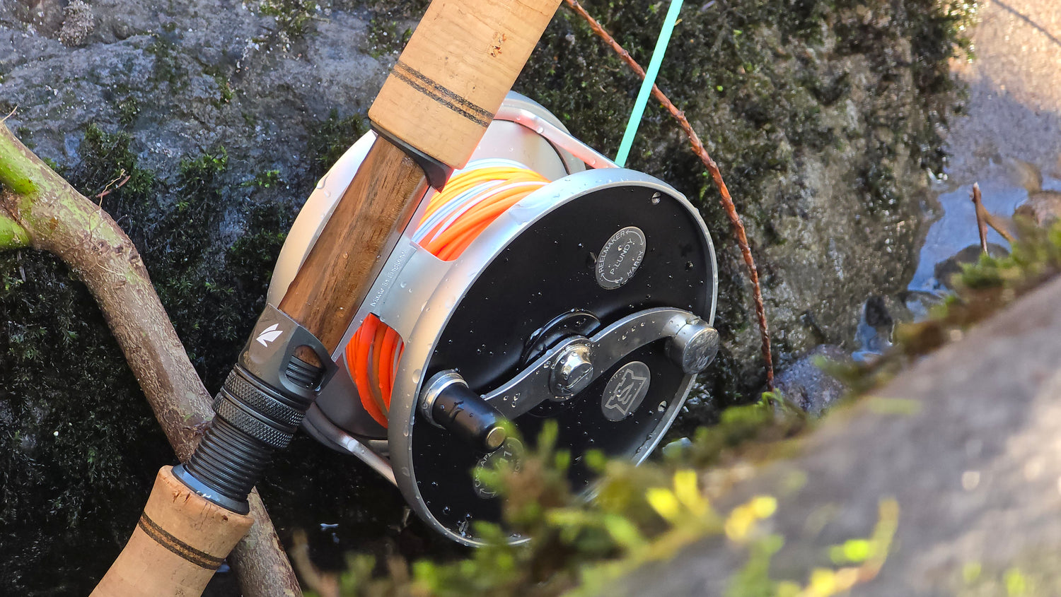 Hatch Fishing reel attached to a Sage fishing rod with a natural river background