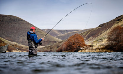 Steelhead angler spey fishing on the Deschutes river with rolling mountains in the background